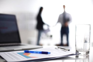 Dizüstü bilgisayar ile ağıl üstünde okul sırası, arka planda duran iki iş adamları