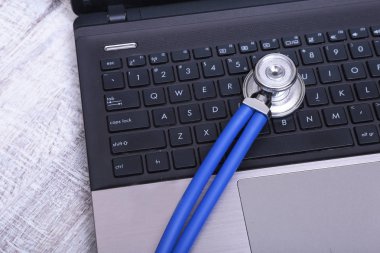 Beyaz ahşap bir masa üstünde a laptop yanında sağlık stetoskop