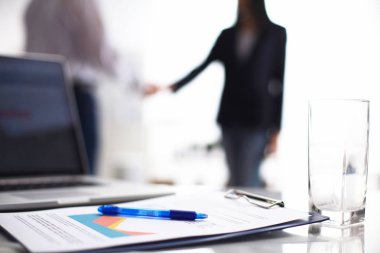 Dizüstü bilgisayar ile ağıl üstünde okul sırası, arka planda duran iki iş adamları