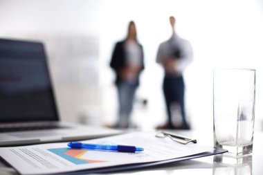 Dizüstü bilgisayar ile ağıl üstünde okul sırası, arka planda duran iki iş adamları