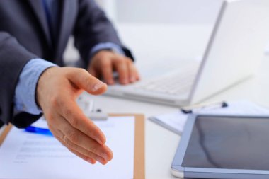 El sıkışın, masanın üzerinde oturmak sunan bir takım elbise giyen adam