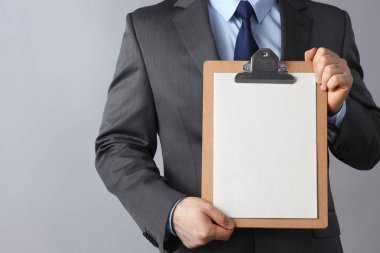 Ayakta gri arka plan üzerinde izole klasörle genç adam