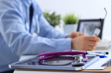 Erkek doktor masasında oturan sağlık stetoskop ile bir dizüstü bilgisayar kullanarak