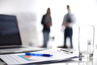 Dizüstü bilgisayar ile ağıl üstünde okul sırası, arka planda duran iki iş adamları