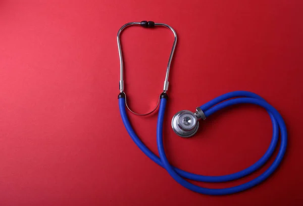 Medical blue stethoscope isolated on red background