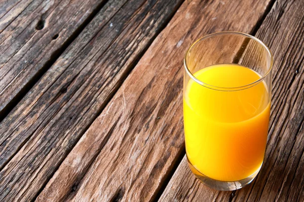 Vaso de zumo de naranja sobre fondo de madera. Espacio de copia — Foto de Stock