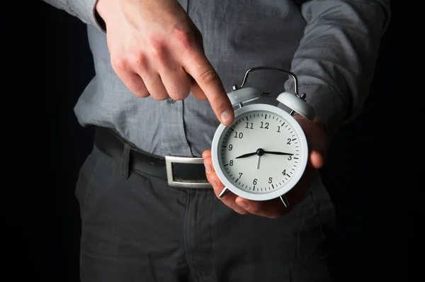 Businessman holding a clock reminding about deadline