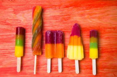 Kırmızı ahşap arka plan üzerinde renkli Buz lolly