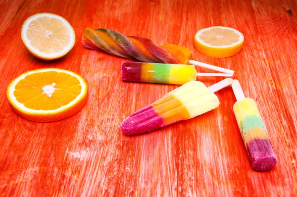 Colorful ice lolly on a red wooden background — Stock Photo, Image