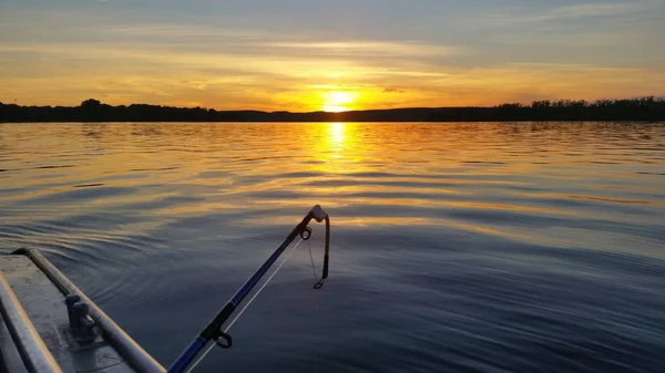 Uma reunião de uma bela alvorada em um rio no verão em um barco com uma vara de pesca — Fotografia de Stock