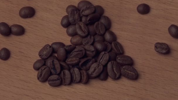 Кофейные зерна в форме сердечка вращаются на доске — стоковое видео