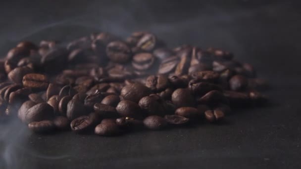 Кофейные бобы крутятся на доске в дыму — стоковое видео