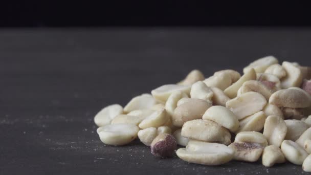 Jordnötter med salt snurrar på en mörk bakgrund — Stockvideo