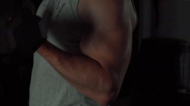 Kaslı adam dambılı kaldırıyor.