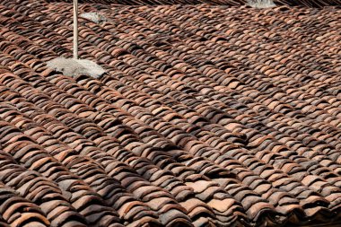 Eski kahverengi kiremitler evin çatısına yakın, eski bir çatı, çatı inşa etmek için geleneksel etnik malzemeler.