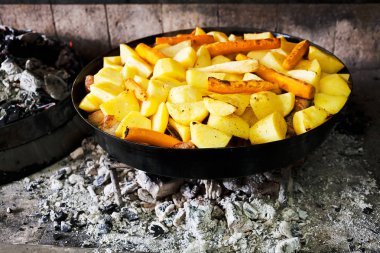 Sıcak kömürlerin üzerinde demir bir tencerede patates hazırlarken, sığ alan derinliğine dikkat edin.