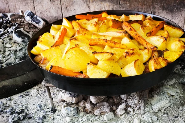 preparing potatoes in an iron pot on hot coals, note shallow depth of field