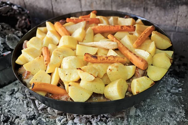 preparing potatoes in an iron pot on hot coals, note shallow depth of field