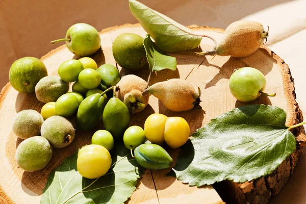 miscellaneous not ripe fruit in a pile on a wooden board