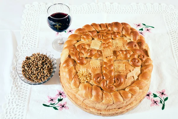Geleneksel ortodoks pastası. Bir bardak kırmızı şarap ve dantel kumaşın üzerinde tahıl.
