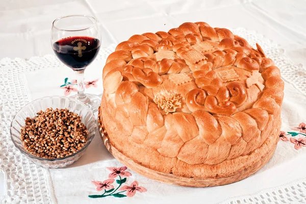 Orthodox traditional cake  with a glass of red wine and grain on the lace cloth