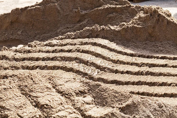 sand in construction with traces of buckets for loading on excavator