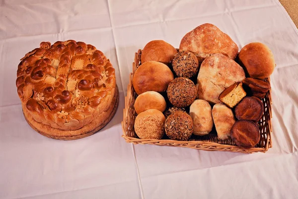 various kinds of bread  made from various flour in  a wicker basket next Slava cake