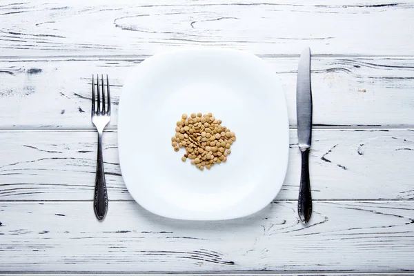 Немного высушенной чечевицы лежит на тарелке. Красиво сервированный стол для человека, который хочет похудеть. Диета для срочной и быстрой потери веса . — стоковое фото
