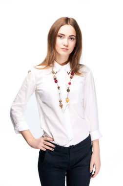 Beyaz bir gömlek, siyah pantolon ve beyaz zemin üzerine boncuk kadında. Güzel bir genç kız portresi. Moda model stüdyo yılında bir fotoğraf için poz. Office için şık modern giyim.