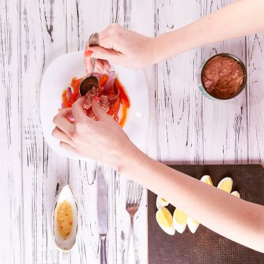 Cook tatlı biber, olgun domates ve kırmızı soğan salatası konserve ton balığı koyar. Kilo kaybı için sağlıklı bir salata pişirme adım adım süreci. Et mezesi, balık, sebze, baharat. 