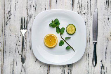 Birtakım ürünler Detoks için ana içecek yapmak için. Bir Bahar Dalı, nane, yeşil salatalık bir halka ve parlak sarı limon beyaz bir plaka üzerinde bir parçası. Kilo kaybı ve vücut detoksifikasyon için