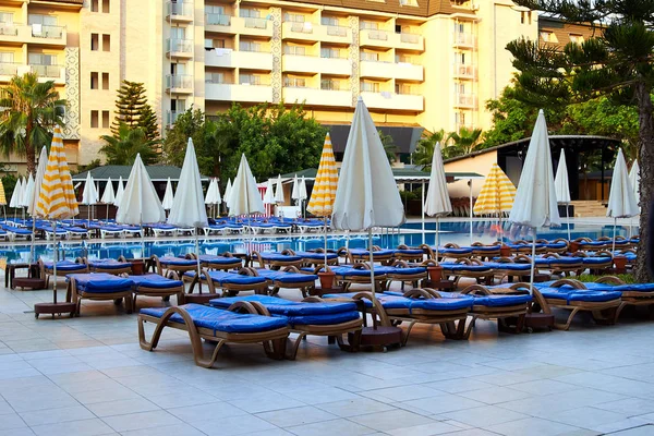 A lot of sun loungers with blue mattresses at the luxurious pool. Umbrellas for protection from the sun. Exclusive resort all inclusive. A typical holiday in Turkey, Egypt, Tunisia, Spain, Italy.