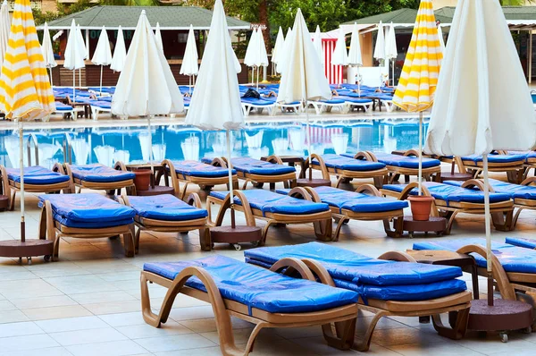 A lot of sun loungers with blue mattresses at the luxurious pool. Umbrellas for protection from the sun. Exclusive resort all inclusive. A typical holiday in Turkey, Egypt, Tunisia, Spain, Italy.