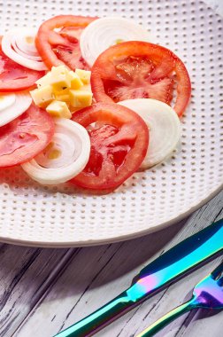 Güzel bahar salata domates, soğan, peynir ve yeşil giyinme. Büyük zarif tabağa yemek. Olağandışı yanardöner çatal bıçak takımı. Bir beslenme uzmanı sağlıklı bir diyet için lezzetli ve kolay yemek.