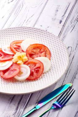 Güzel bahar salata domates, soğan, peynir ve yeşil giyinme. Büyük zarif tabağa yemek. Olağandışı yanardöner çatal bıçak takımı. Bir beslenme uzmanı sağlıklı bir diyet için lezzetli ve kolay yemek.