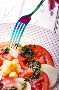 Güzel bahar salata domates, soğan, peynir ve yeşil giyinme. Büyük zarif tabağa yemek. Olağandışı yanardöner çatal bıçak takımı. Bir beslenme uzmanı sağlıklı bir diyet için lezzetli ve kolay yemek.