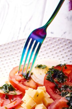 Güzel bahar salata domates, soğan, peynir ve yeşil giyinme. Büyük zarif tabağa yemek. Olağandışı yanardöner çatal bıçak takımı. Bir beslenme uzmanı sağlıklı bir diyet için lezzetli ve kolay yemek.