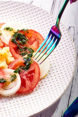 Güzel bahar salata domates, soğan, peynir ve yeşil giyinme. Büyük zarif tabağa yemek. Olağandışı yanardöner çatal bıçak takımı. Bir beslenme uzmanı sağlıklı bir diyet için lezzetli ve kolay yemek.