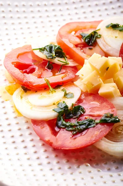 Güzel bahar salata domates, soğan, peynir ve yeşil giyinme. Büyük zarif tabağa yemek. Olağandışı yanardöner çatal bıçak takımı. Bir beslenme uzmanı sağlıklı bir diyet için lezzetli ve kolay yemek.