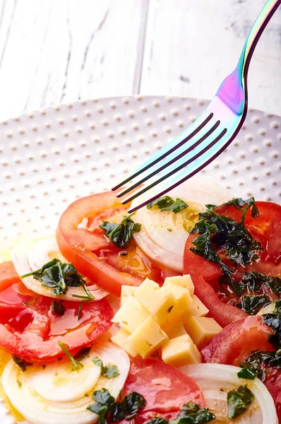 Güzel bahar salata domates, soğan, peynir ve yeşil giyinme. Büyük zarif tabağa yemek. Olağandışı yanardöner çatal bıçak takımı. Bir beslenme uzmanı sağlıklı bir diyet için lezzetli ve kolay yemek.