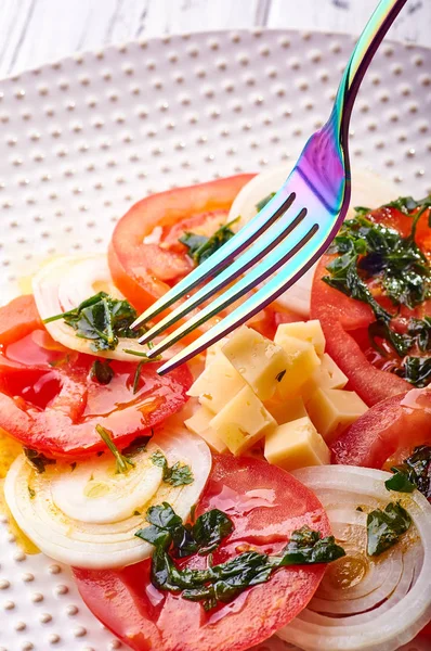 Güzel bahar salata domates, soğan, peynir ve yeşil giyinme. Büyük zarif tabağa yemek. Olağandışı yanardöner çatal bıçak takımı. Bir beslenme uzmanı sağlıklı bir diyet için lezzetli ve kolay yemek.