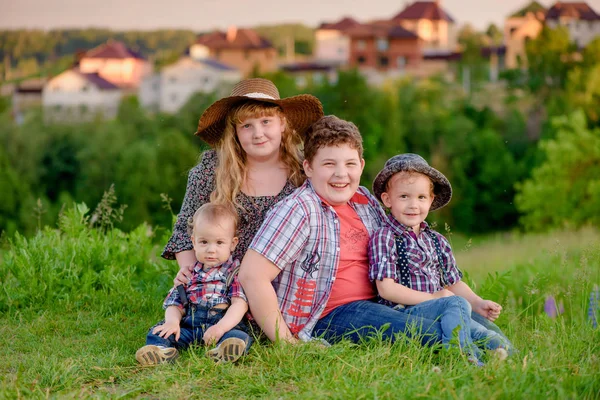 Quatre frères et sœurs drôles dans une prairie sur le fond du village — Photo