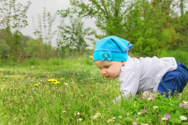 Çiçekli çayır üzerinde oynarken küçük şirin bebek