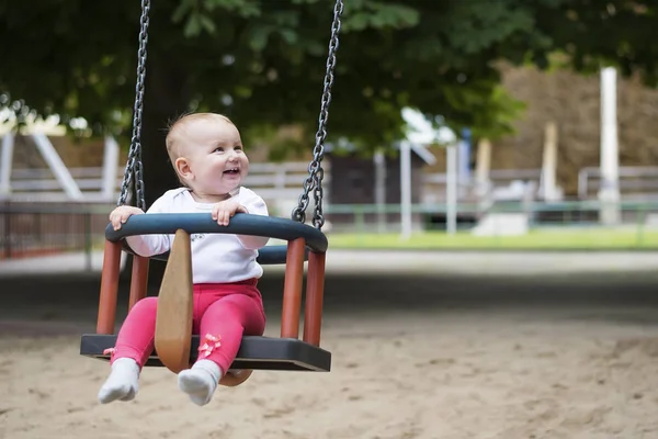 Kleines aktives Kind schwingt fröhlich auf Schaukel im Sommerpark. — Stockfoto