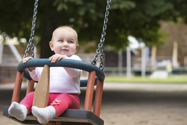 Kleines aktives Kind schwingt fröhlich auf Schaukel im Sommerpark. — Stockfoto