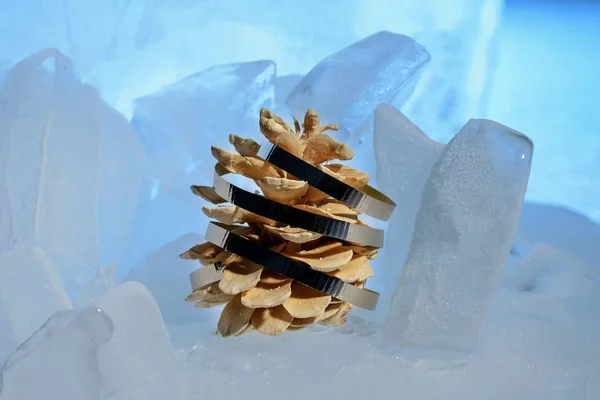 Pine cone decorated with decorative tape on blue ice