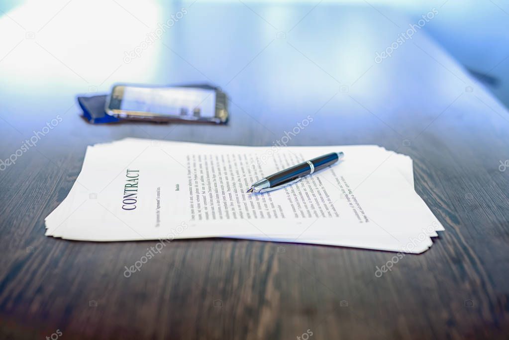 Business contract and black fountain pen on desk, mobile phone i