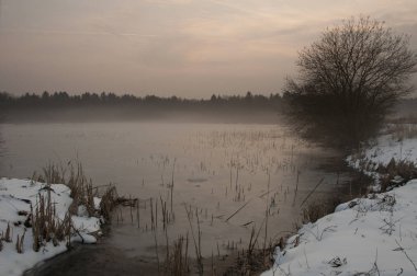 Gün batımında sis gölde kış