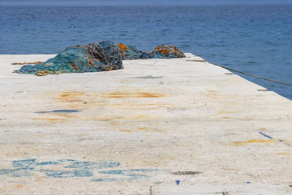Каменный пирс с красочными рыболовецкими сетями и синим морем — стоковое фото