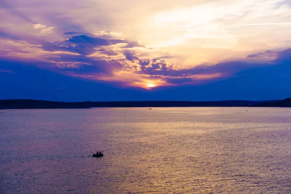 Twee mannen in een opblaasbare kajak peddelen in kleurrijke sunset — Stockfoto